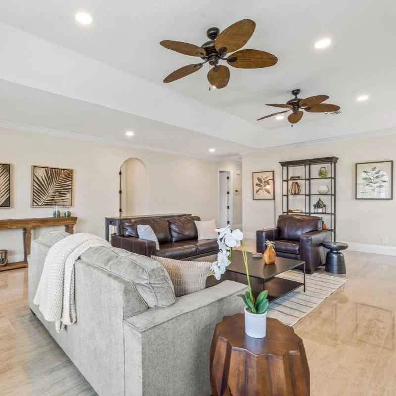 a beautiful living room with a brown couch, a brown side chair, nice leaf paintings on the walls, and a middle table.